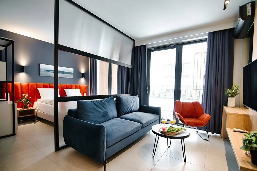 Wykończony apartament: salon z granatową sofą i sypialnia za szklaną ścianką
